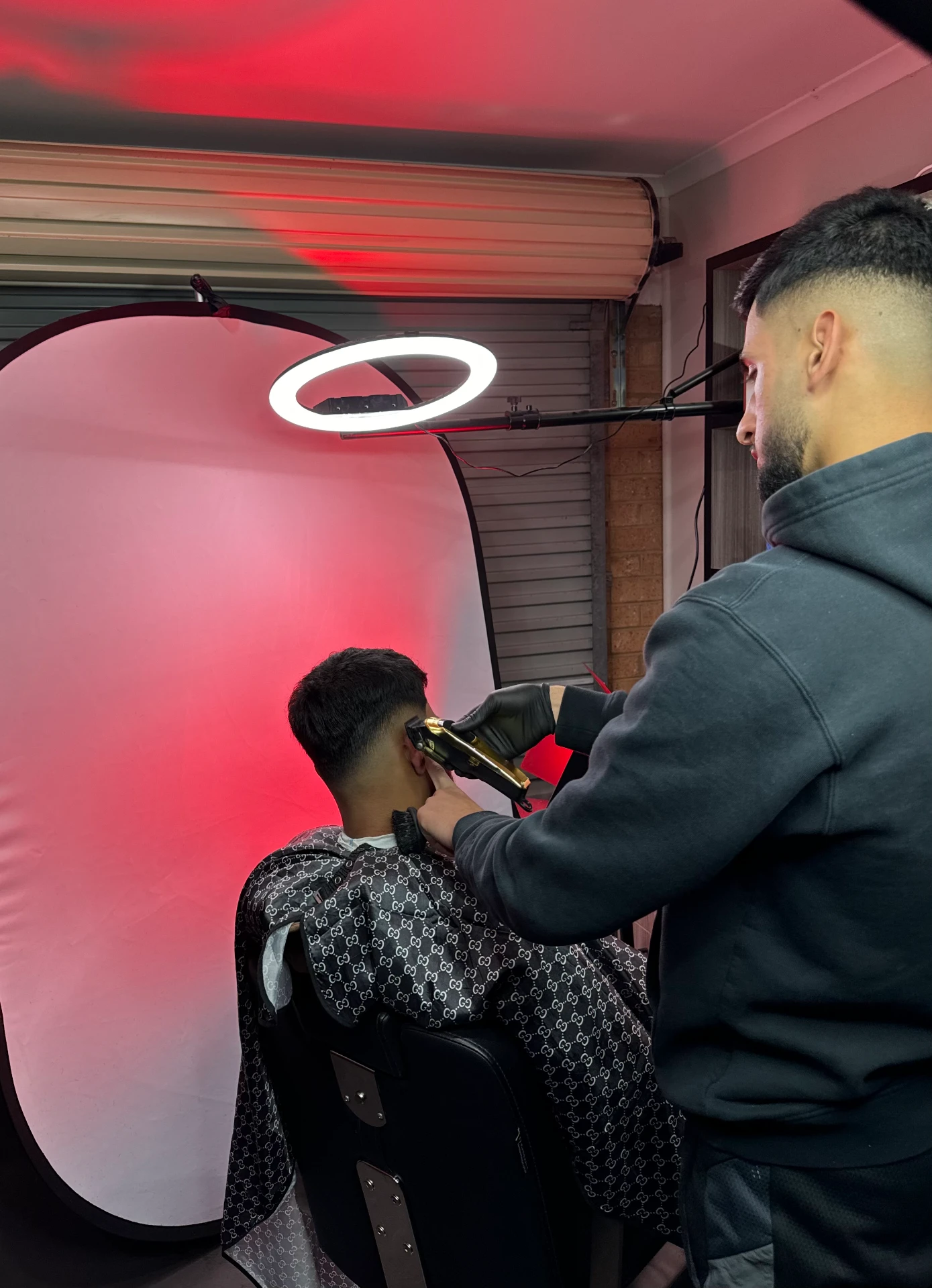 SaFades barber crafting a precision fade against the red studio backdrop